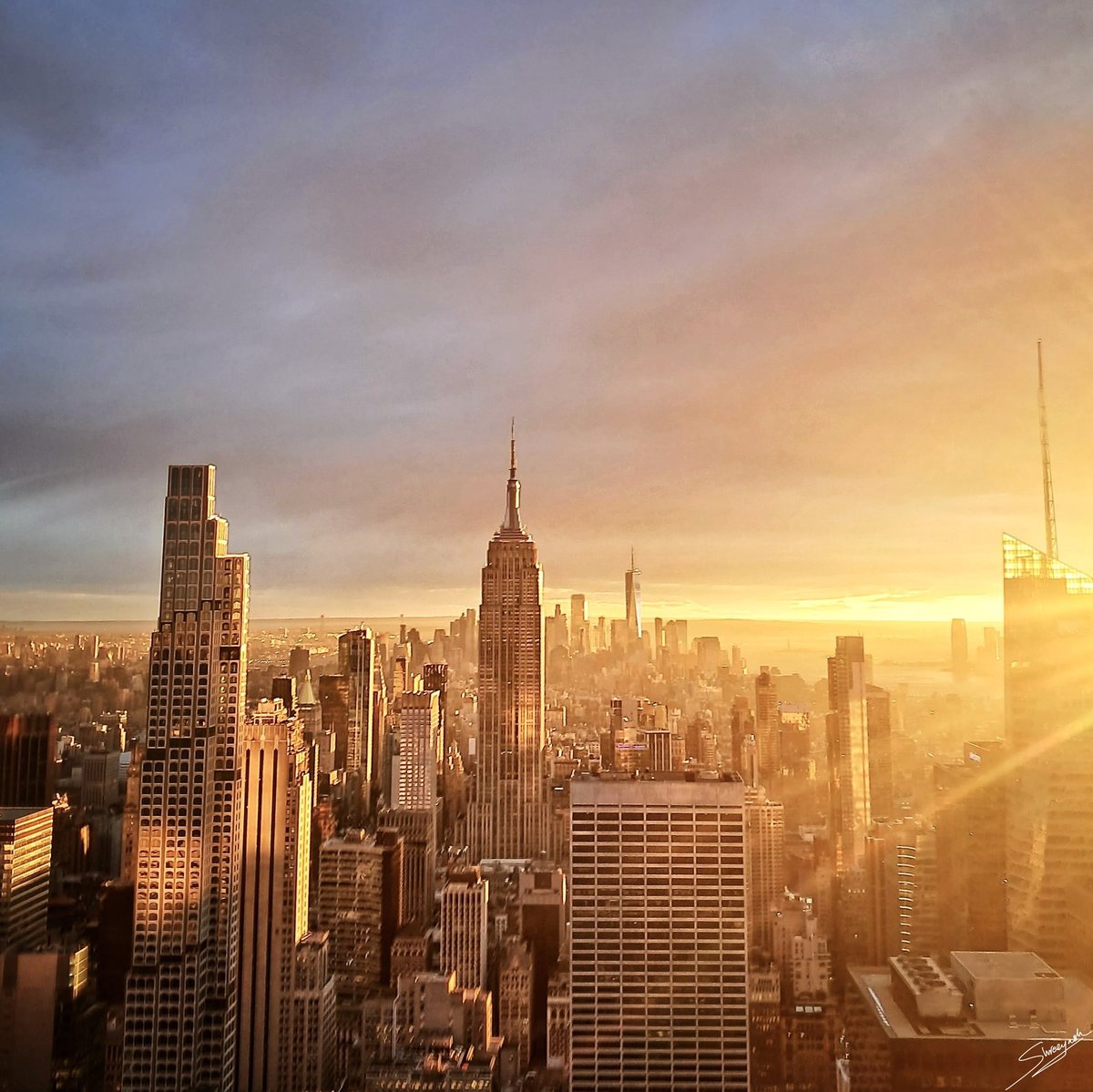 Manhattan skyline in golden light, with the Empire State Building in the foreground and One World Trade Center in the distance.